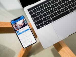 iPhone next to laptop with Facebook app open 